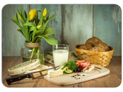 Stůl s proutěným košem plným pečiva, sklenicí mléka, sýrem, zeleninou a vázou s tulipány