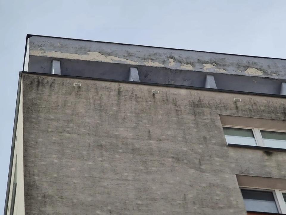Poškodené a odlupujúce sa povrchové vrstvy vo vrchnej časti domu pred opravou