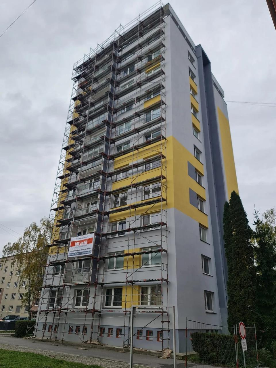 Obnova sivožltého bytového domu v Martine v roku 2023, lešenie a označenie firmy JM Refit
