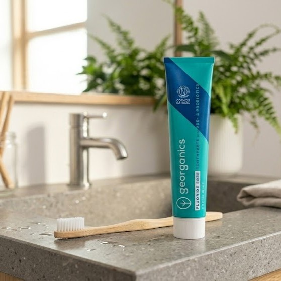 Georganics fluoride-free toothpaste with prebiotics and probiotics on bathroom sink with bamboo toothbrush