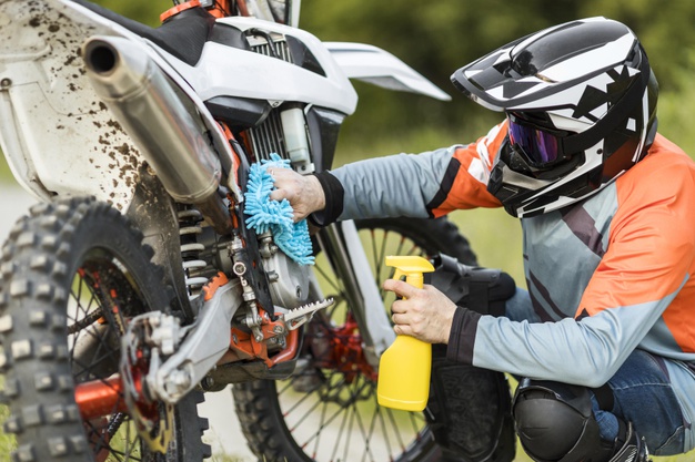 active-man-cleaning-motorbike-outdoors_23-2148585536