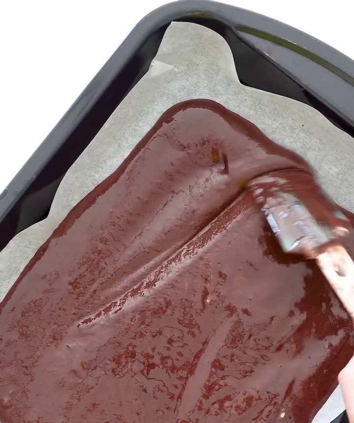 Čokoládové těsto rozetřené na plechu s pečicím papírem