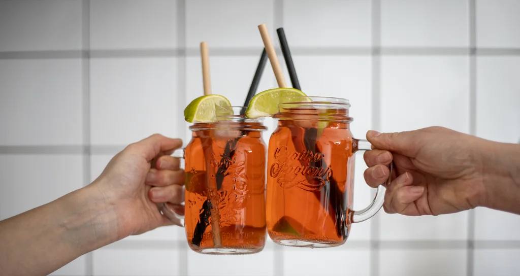 Domácí limonáda ve dvou zavařovacích sklenicích s uchem, brčky a plátky limetky