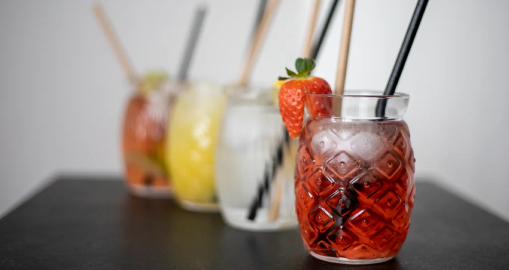 Domácí limonády v designových sklenicích s brčky a jahodou na ozdobu