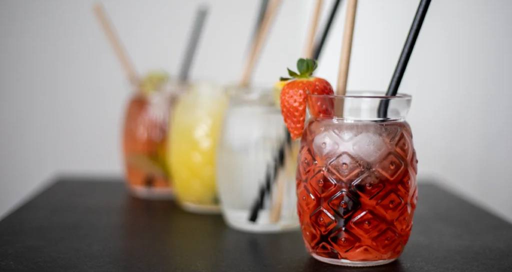 Domácí limonády v designových sklenicích s brčky a jahodou na ozdobu
