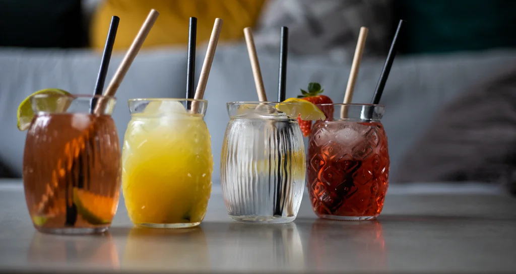 Čtyři domácí limonády v barevných sklenicích s brčky a ovocnou ozdobou