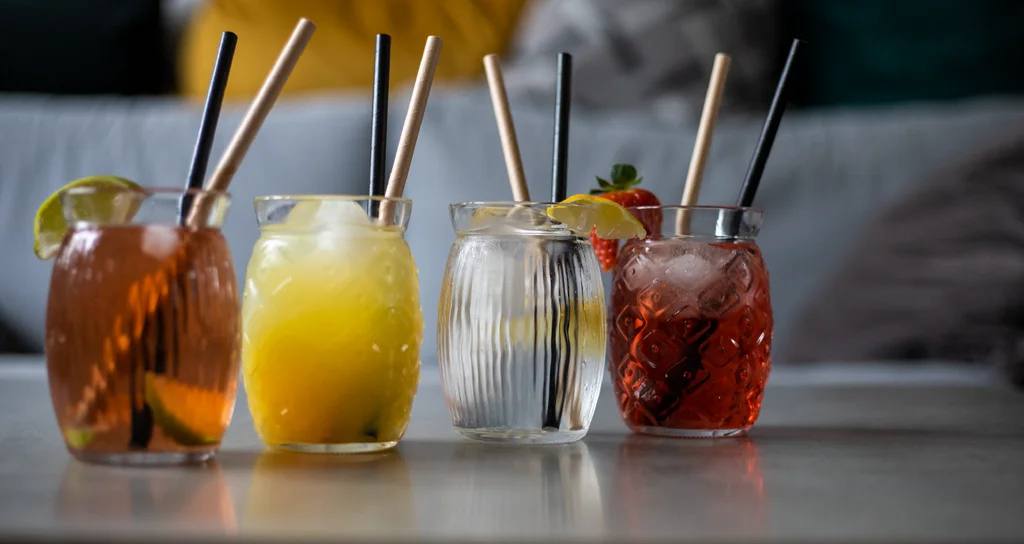 Čtyři domácí limonády v barevných sklenicích s brčky a ovocnou ozdobou