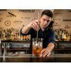 Firefly Young bartender actively mixing a cocktail in a crystal glass using a long bar spoon, 893150
