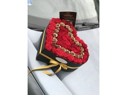 Luxusní květinový box Red Black Heart ve tvaru srdce, kombinace rudých růží a zlatých akcentů, zdobený elegantní zlatou stuhou, aranžovaný na světlém pozadí.