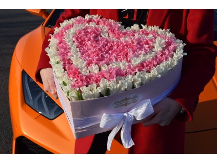 Luxusní „Lovely Tulips Box“ ve tvaru srdce, růžovo-bílý design umístěný na oranžovém sportovním autě.