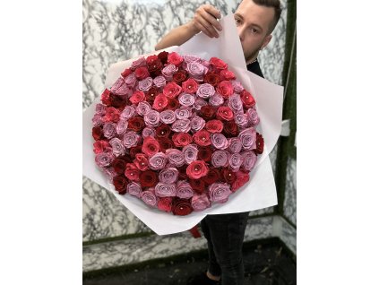 Luxusní puget 101 růží ve třech elegantních odstínech – červené, fialové a růžové, prezentovaný na pozadí stylové květinářské dekorace.