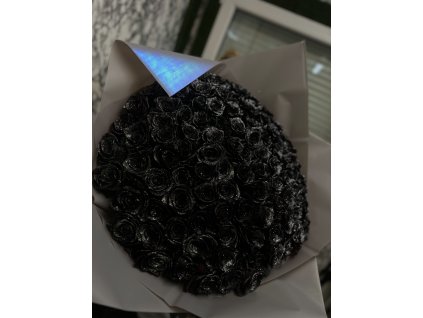 Speciální třpytivý puget Black z lesklých černých růží, elegantně zabalený v bílé fólii s holografickým detailem, vystavený na stole.