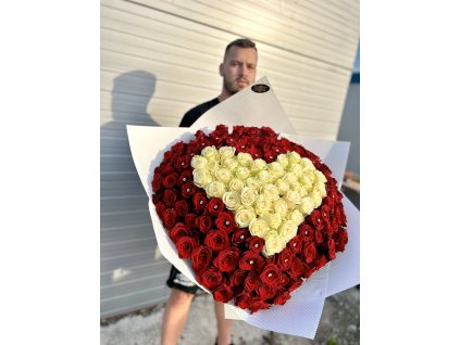 Velkolepá kytice ve tvaru srdce z bílých růží lemovaná rudými růžemi, prezentovaná mužem před světlým pozadím.
