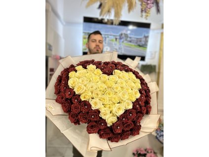 Kytice růží ve tvaru srdce – světle dvětlé srdce obklopené třpytivými rudými růžemi, prezentována floristem před výlohou květinářství.
