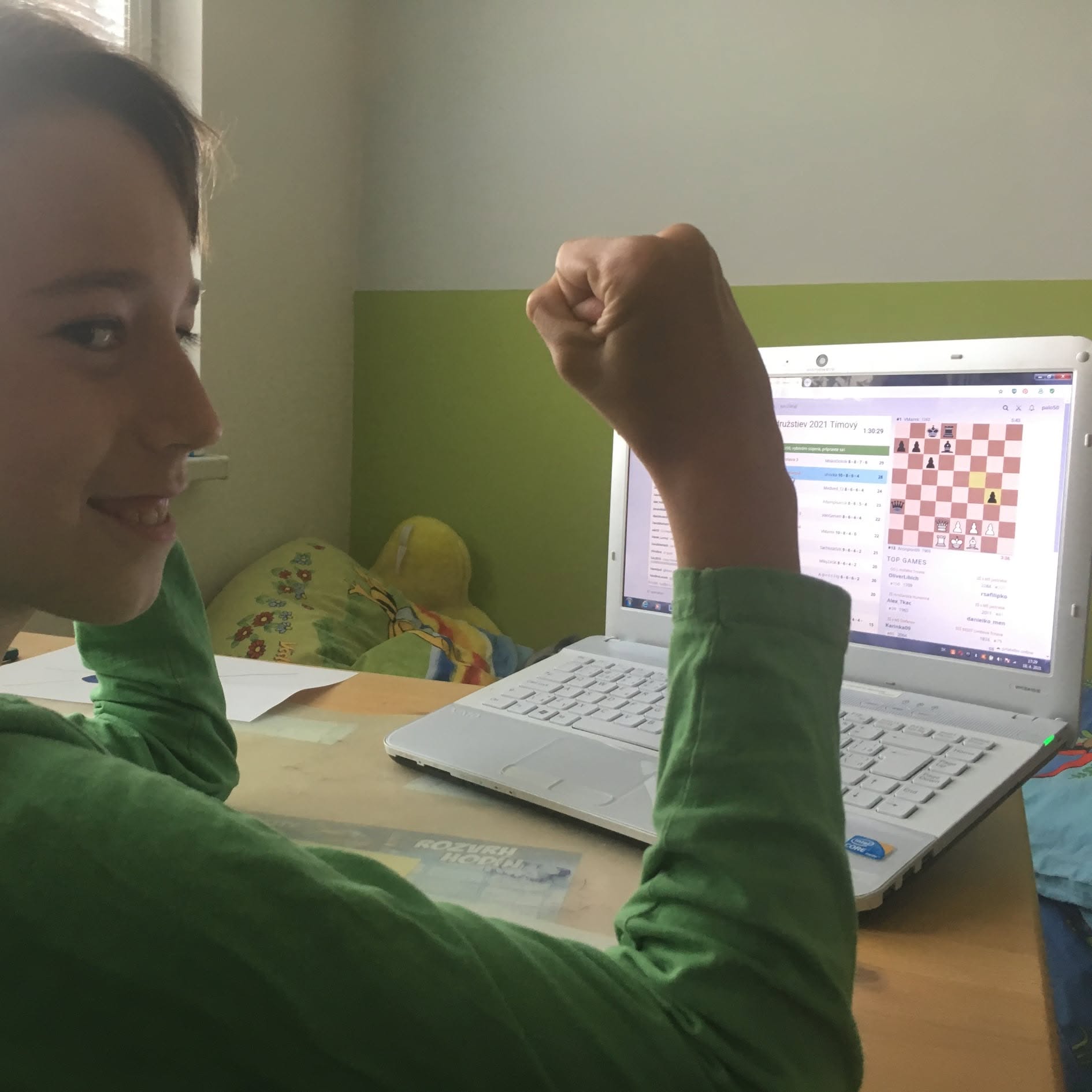 Copil care se bucură de o partidă câștigată în șahul online pe laptop