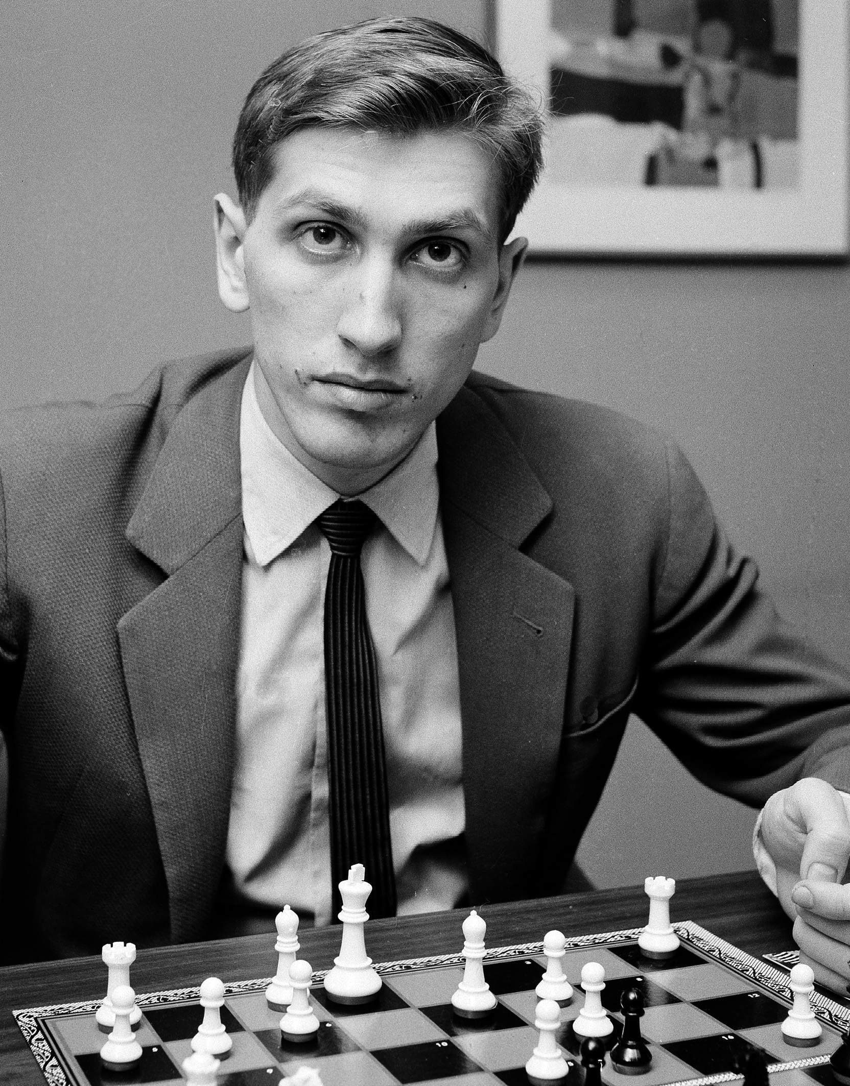 Portret alb-negru al lui Bobby Fischer în fața tablei de șah