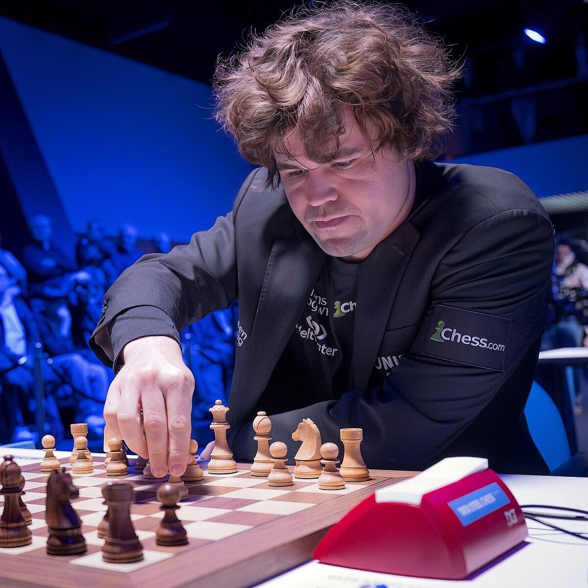 Magnus Carlsen mută o piesă la tabla de șah în timpul unui turneu