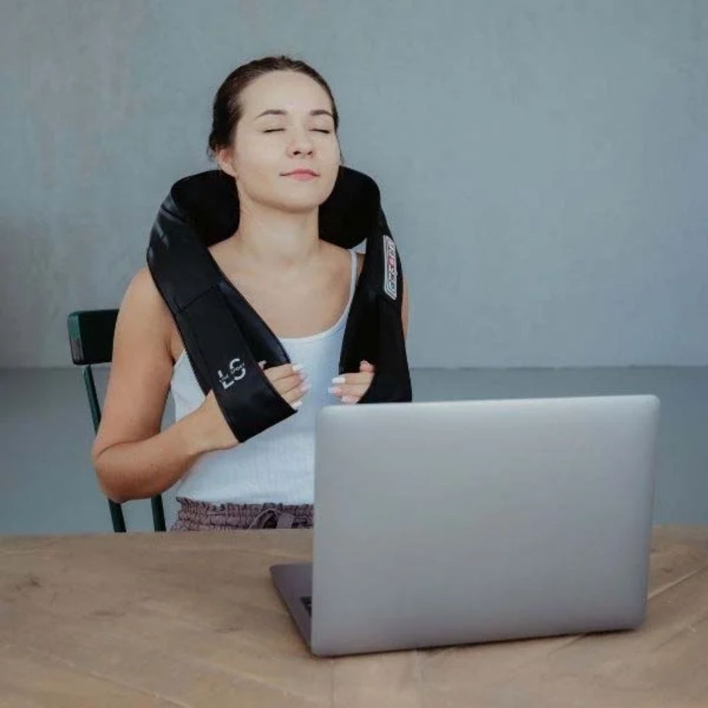Žena používa shiatsu masážny prístroj Line Sport PRO+ na krk a šiju pri práci s počítačom