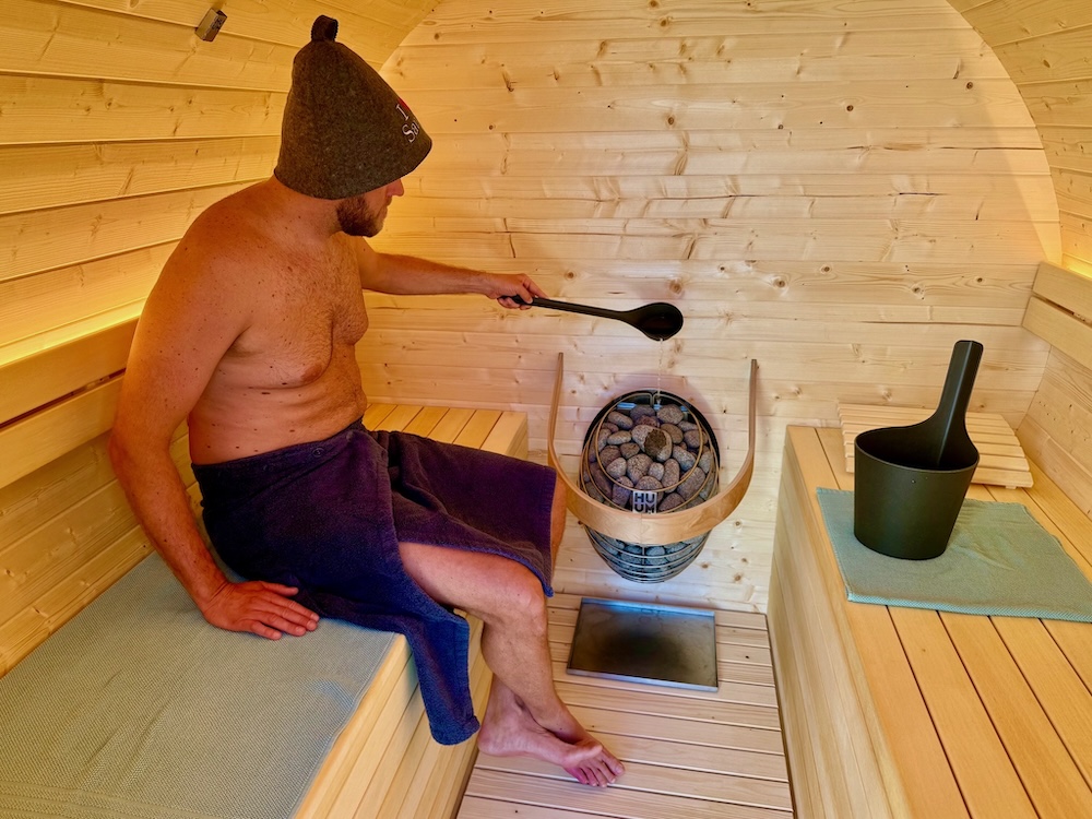 Relaxace a polévání kamenů v sudové sauně s elektrickými kamny