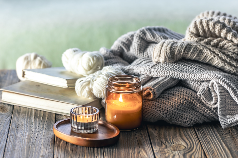 home-composition-with-burning-candles-knitted-elements-books