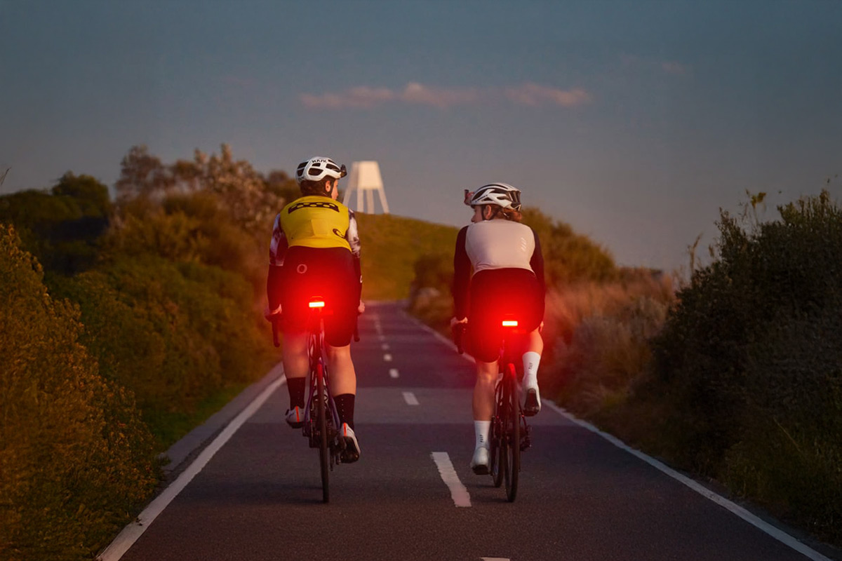 Cyklisté s rozsvíceným zadním světlem Knog Blinder Link při jízdě za soumraku