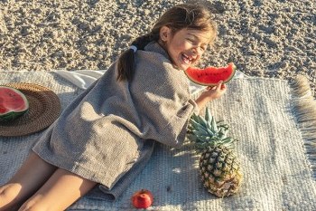 little-girl-eats-fruit-lying-blanket-beach_600x400_450x300_350x233