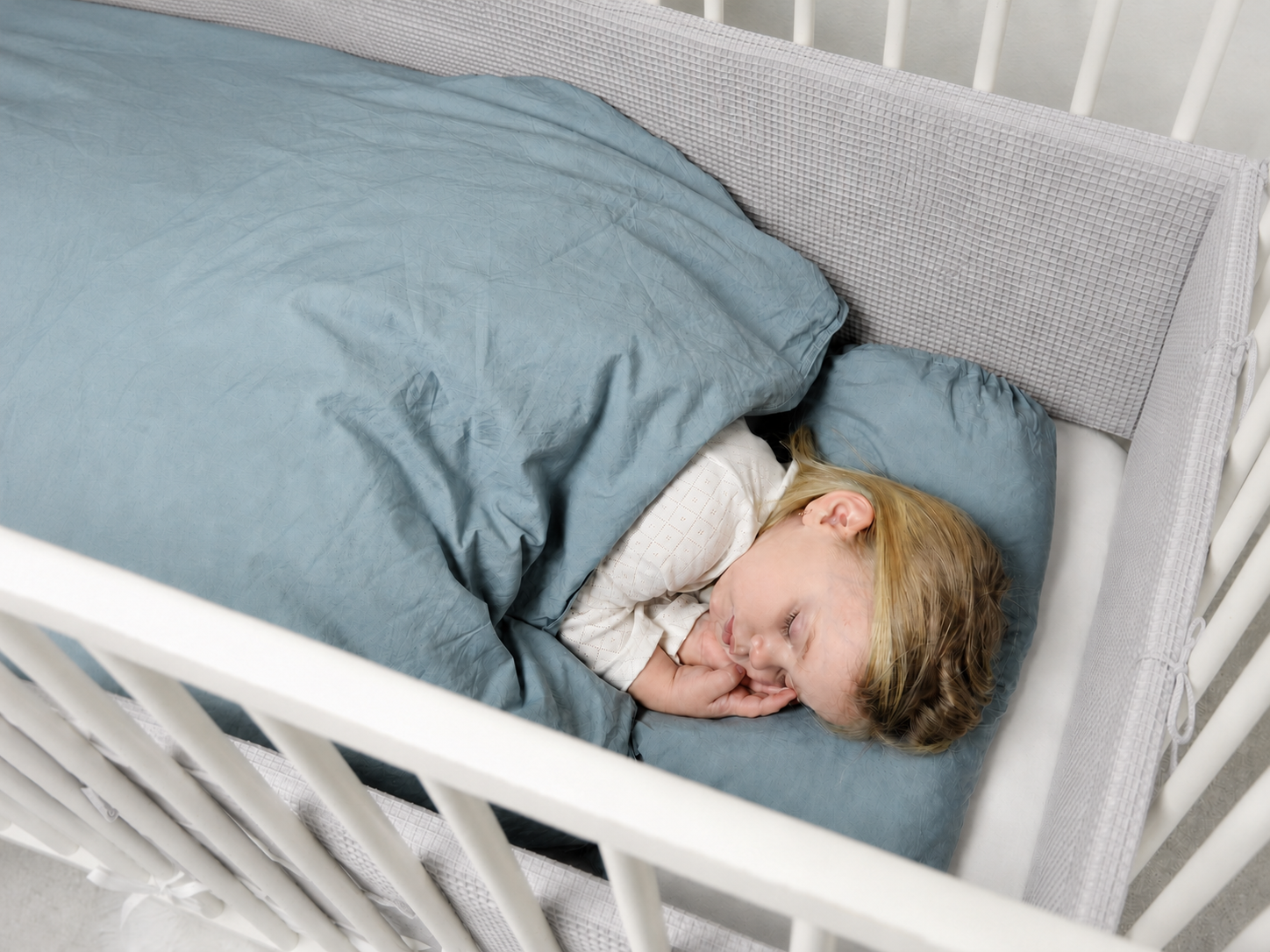Dítě spí v postýlce s pevným mantinelem sleepsheep