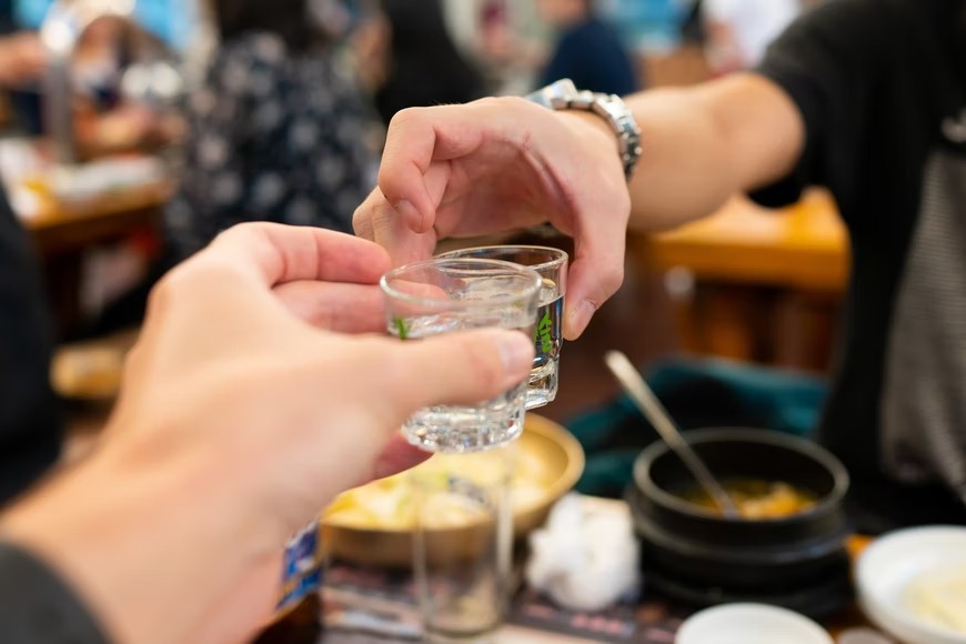 dvaja ľudia pripijajúci si pohárikmi alkoholu