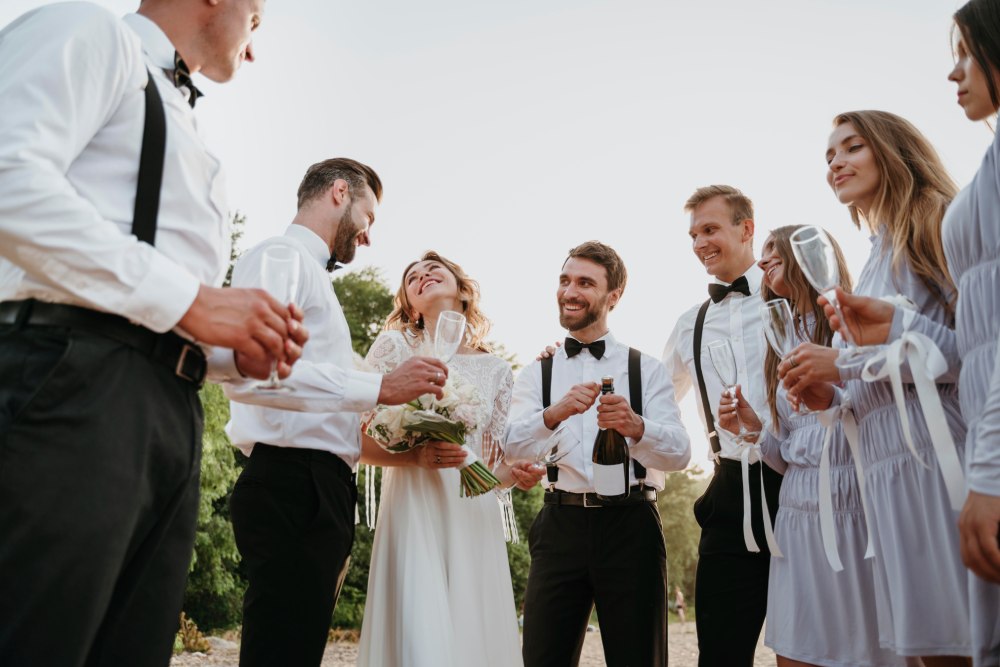 ženích a nevesta si pripíjajú šampanským so svadobčanmi 