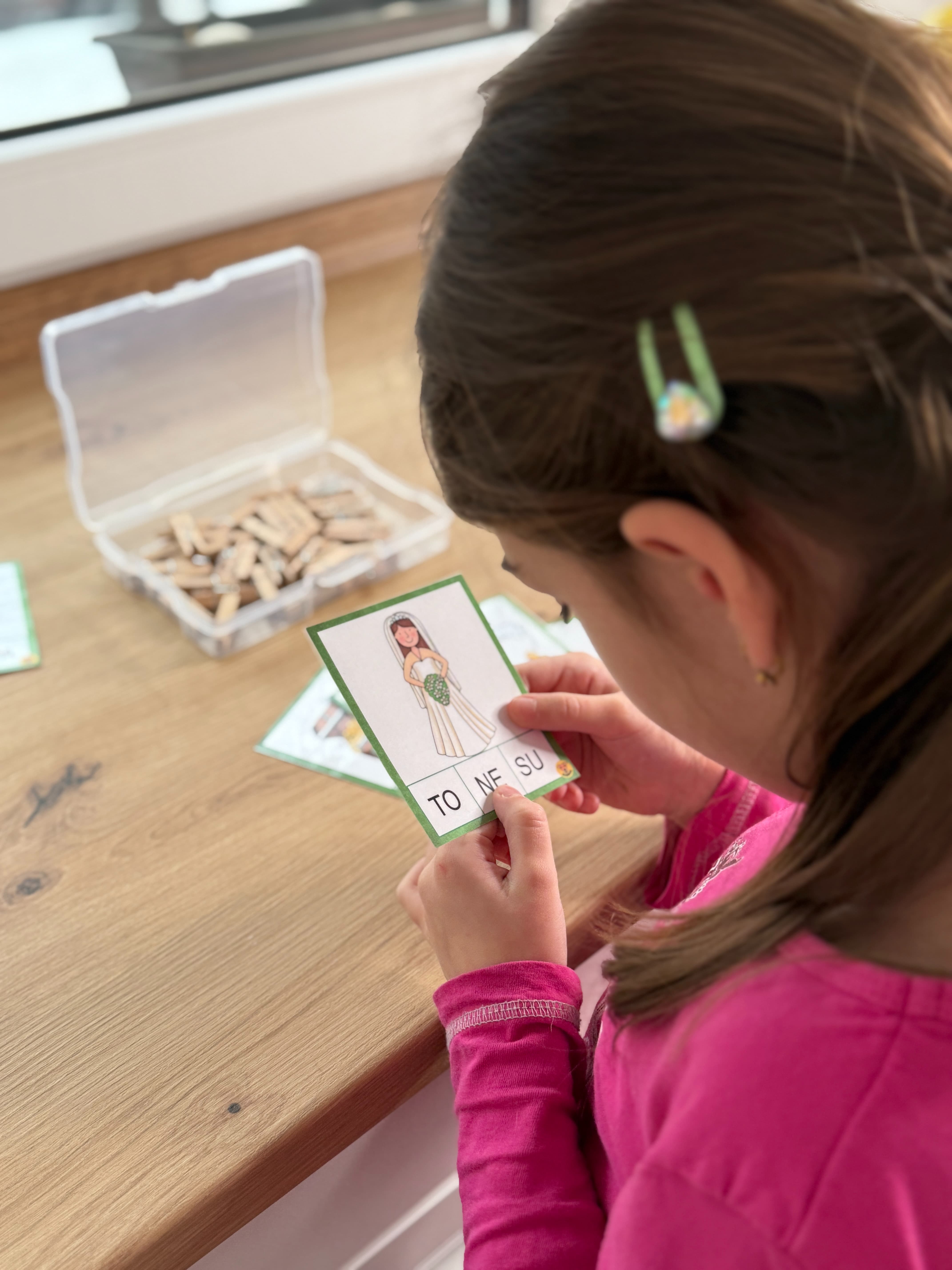 Prvňák procvičuje slabiky pomocí kolíčků na kartičkách