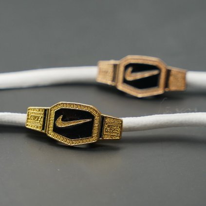 Close-up of gold motion-mark lace charm attached to laces — lightweight metal pendant with secure clamp; compatible with Nike Air Force 1, Dunk, Air Jordan and Air Max low-tops.