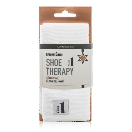 White microfiber cleaning towel laid next to a sneaker cleaning kit
