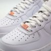 Orange AF1 pastel metal lace tag providing a bright contrast on white laces
