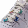 Butterfly shoelace charms threaded onto white flat laces in a playful layout