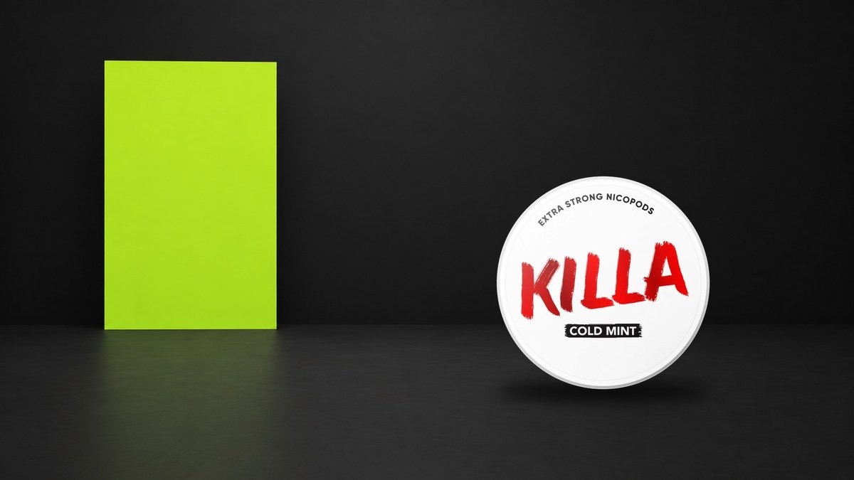 Plechovka Killa Cold Mint Extra Strong vedle limetkové plochy na černém pozadí