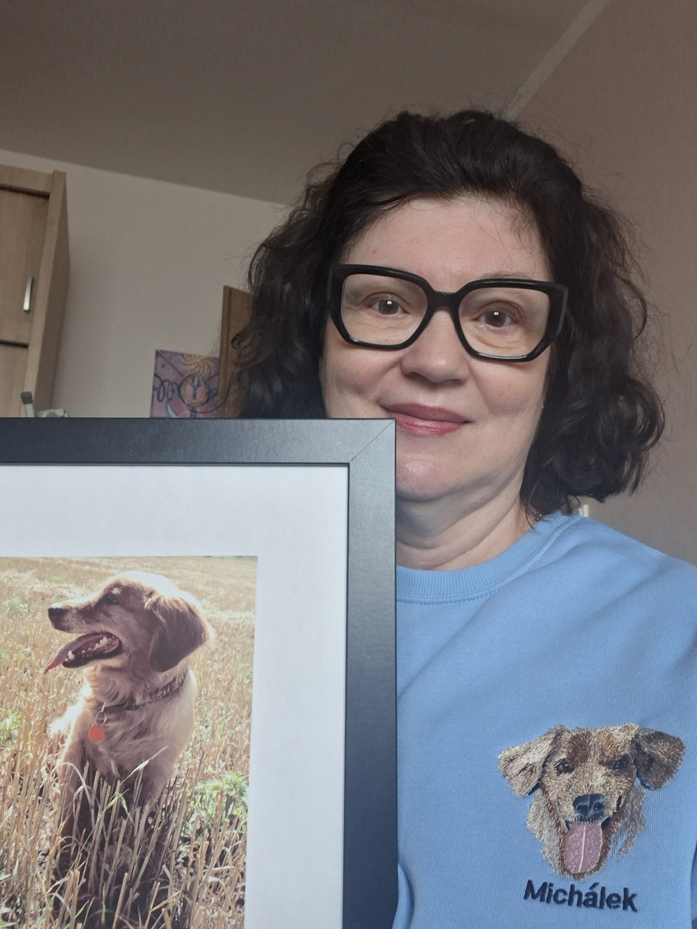 Žena v modré mikině s výšivkou pejska Michálka a jeho fotografií