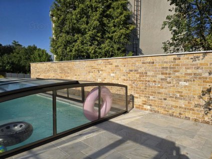 Stone wall cladding Travertine Gold used as elegant poolside wall with warm golden tones.