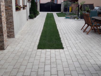 Garden patio slabs in Marble Saturn forming a long path between buildings with a lawn stripe, alley.