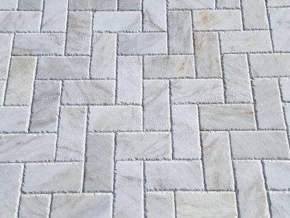 Patio pavers in Marble Alexandria with a cool white tone laid in a herringbone layout on a terrace.