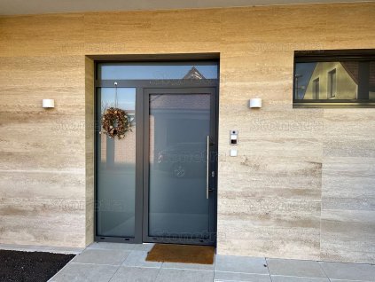 Exterior entrance wall clad in warm natural stone – Travertine Classic Light VC large-format tiles.