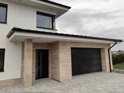 Modern house entrance with columns and façade clad in Travertine Classic Royal VC large-format tiles, unfilled and honed.