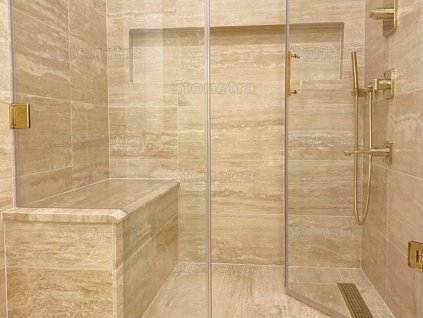 Walk-in shower with bench clad in Travertine Classic Beige Premium VC large-format tiles, unfilled and honed.