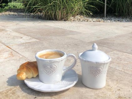 Natural stone patio with Travertine Noche French pattern on a terrace, close view.
