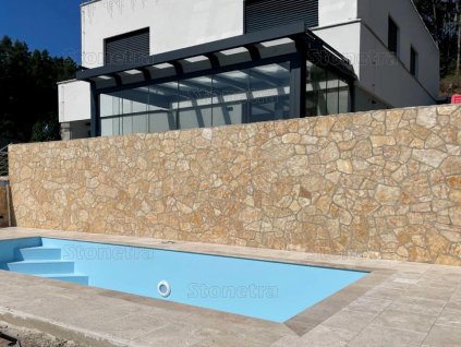 Poolside retaining wall finished with tumbled irregular limestone — Limestone Antik 15–50 cm, 2–3 cm natural stone cladding.