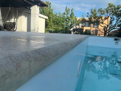 Pool coping Travertine Classic used around a modern swimming pool, showing the smooth stone edge above the waterline.