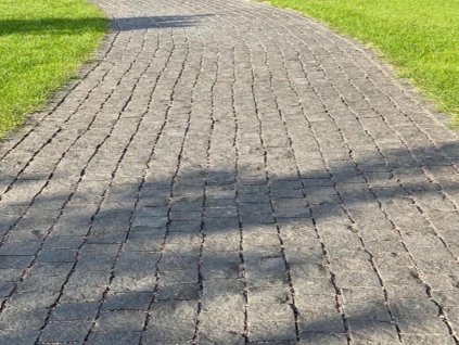 Curved pedestrian path finished with Granite Black cobblestones 7–9 cm, traditional setts with riven texture.