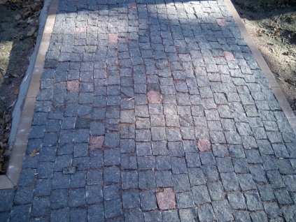 Historic-style walkway paved with small-format Granite Black cobblestones 4–6 cm, tight joints for a durable natural-stone surface.