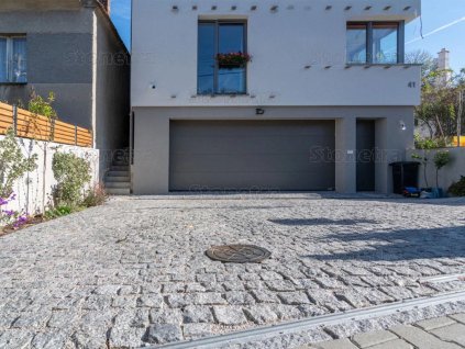 Residential driveway finished with Granite Grey cobblestones 8–11 cm, tight joints and riven texture.