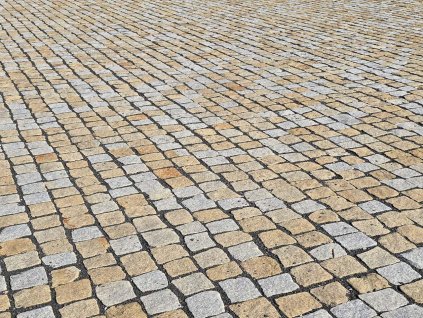 Close view of plaza surface in yellow-grey granite cobblestones 8–11 cm — heavy-duty natural-stone paving.