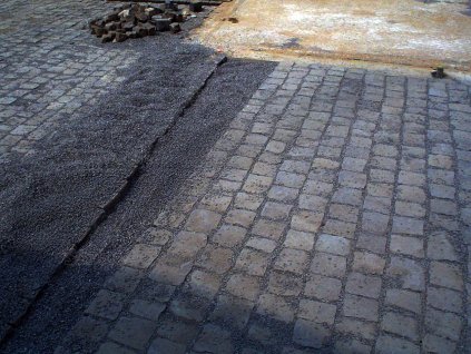 Driveway under construction with medium-format black basalt cobblestones (15–17 cm, 8 cm thick) heavy-duty natural-stone surface.